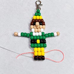 Free pony bead Christmas buddy elf pattern showing an alternate cord path that brings both ends together for one less-prominent finishing knot.