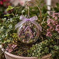 Fairy garden fillable ornament craft project decorated with flowers and miniature accessories for enchanted woodland and miniature world creations.